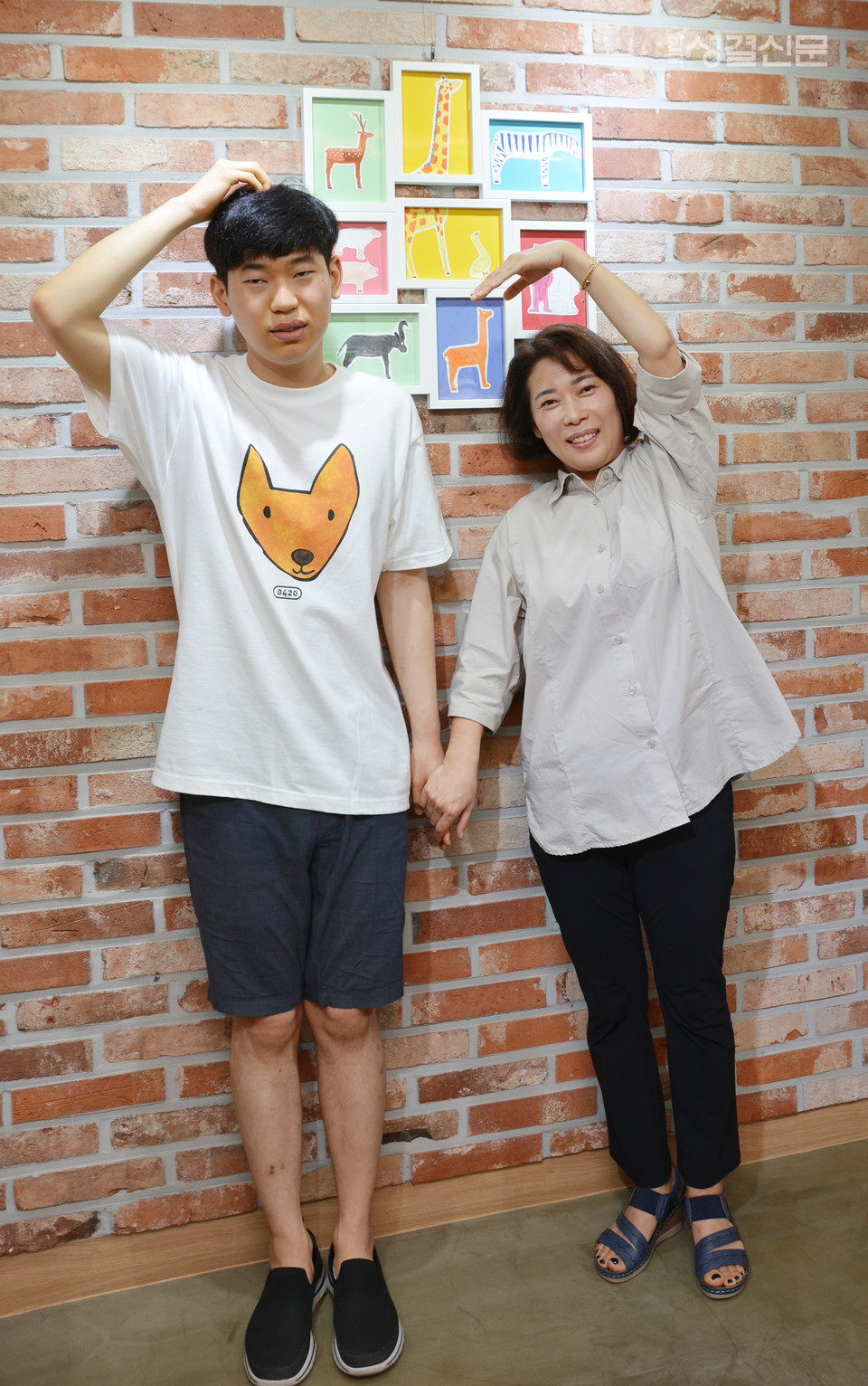                       발달장애인 이상욱 작가와 엄마 조미화 집사가 머리 위로 하트를 그리고 있다.