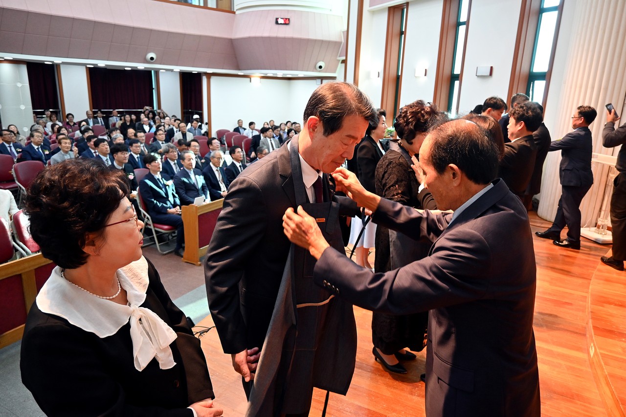 장로장립식에서 ‘평생을 겸손으로 허리를 동여매라’는 의미를 담아 신임 장로들에게 앞치마를 입혀주고 있는 선배 장로들.