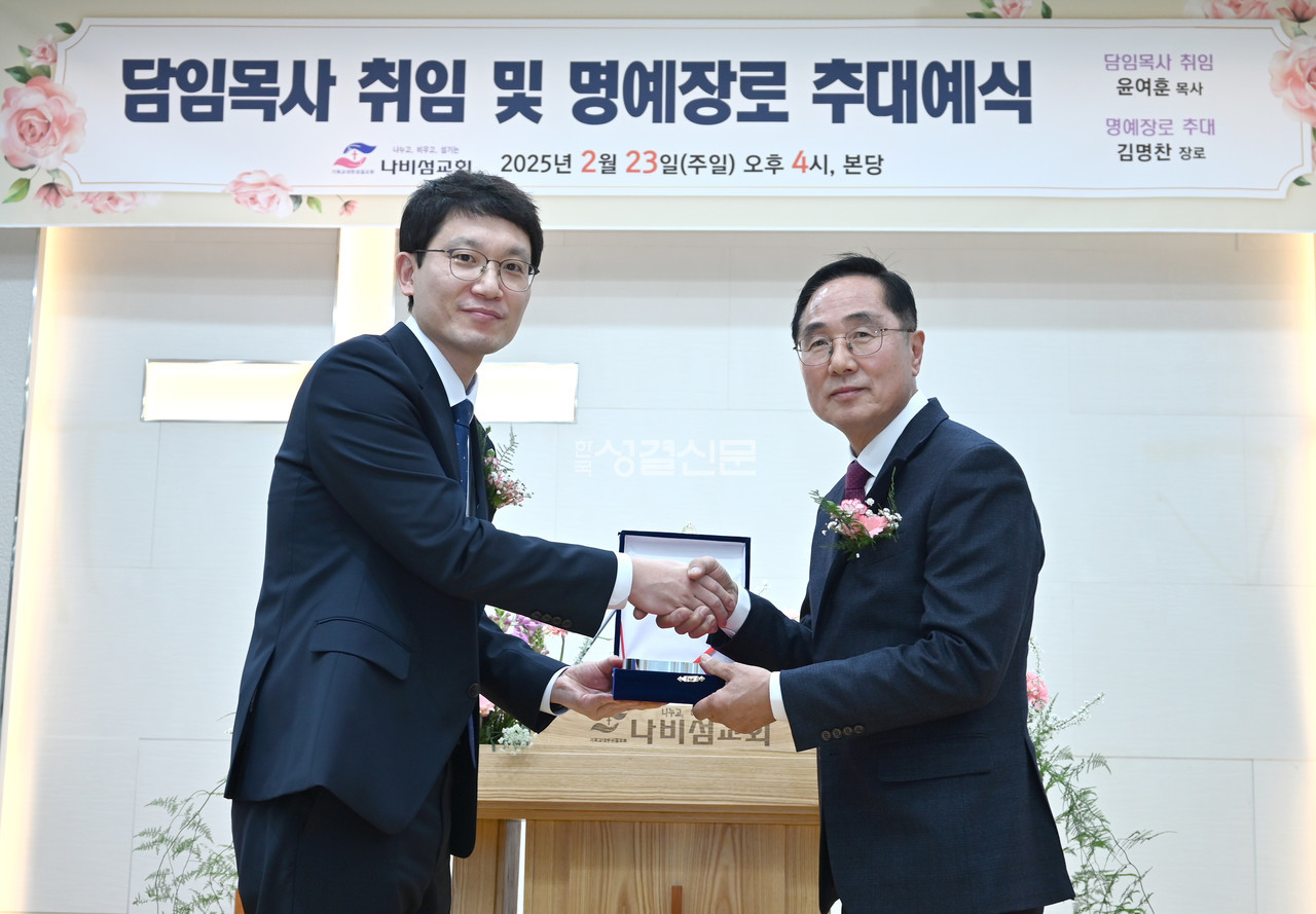 나비섬교회 새 담임 윤여훈 목사가 김명찬 명예장로에게 추대패를 전달하고 있다.