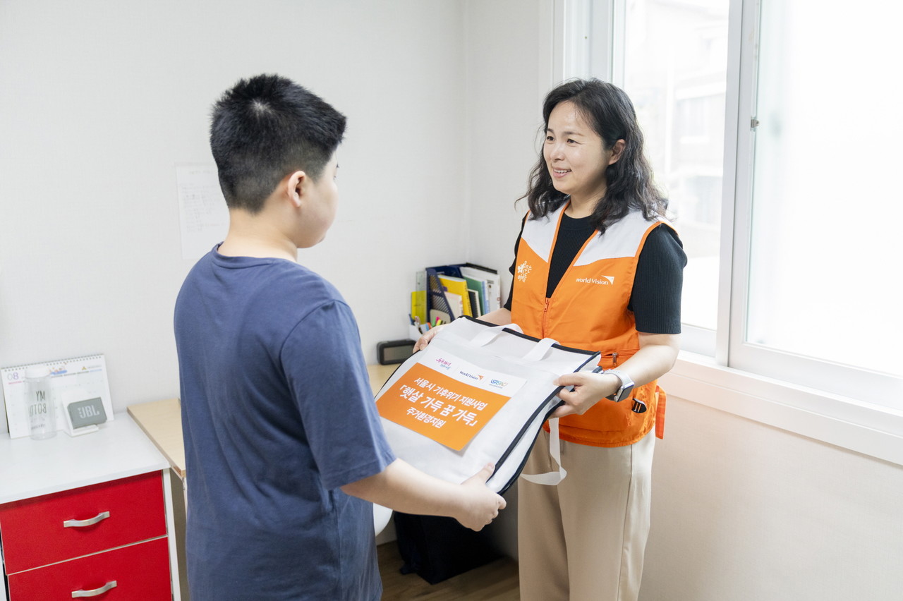 월드비전이 서울시 기후위기 취약아동 미래지원사업 '햇살 가득 꿈 가득' 우수사례 최우찬(가명) 아동 가정을 방문해 주거환경지원비를 전달하고 있는 모습. (사진=월드비전 제공)